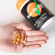 Hand holding capsules with Rose-Hip Vital supplement bottle in the background
