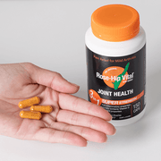 Rose-Hip Vital Joint Health supplement bottle with capsules on a hand against a white background